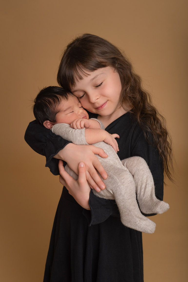 stolze 7 jährige Schwester mit 7 tage altem Baby auf dem Arm