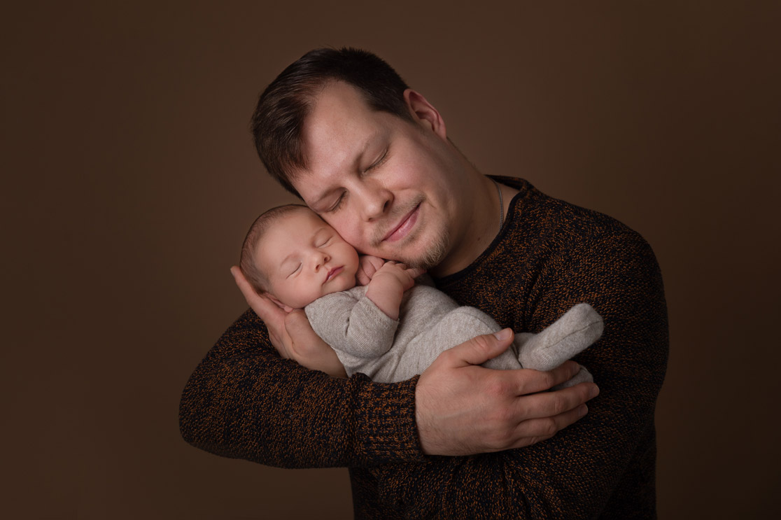 Papa kuschelt liebvoll mit seinem wenige Tage alten Sohn