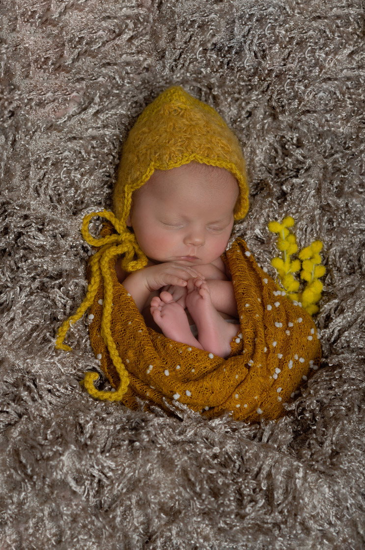 Babymädchen mit gelber Strickmütze in Kuschelfell