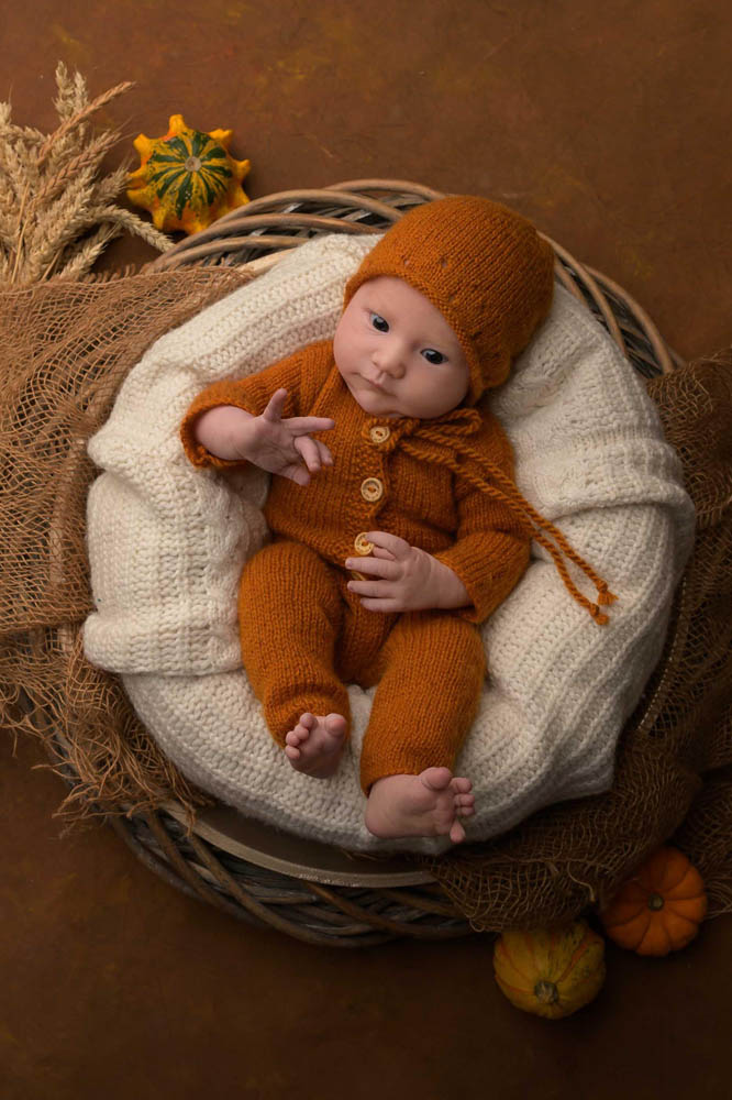Süßer neugeborener Junge in einem Korb mit Bärchen in der Hand