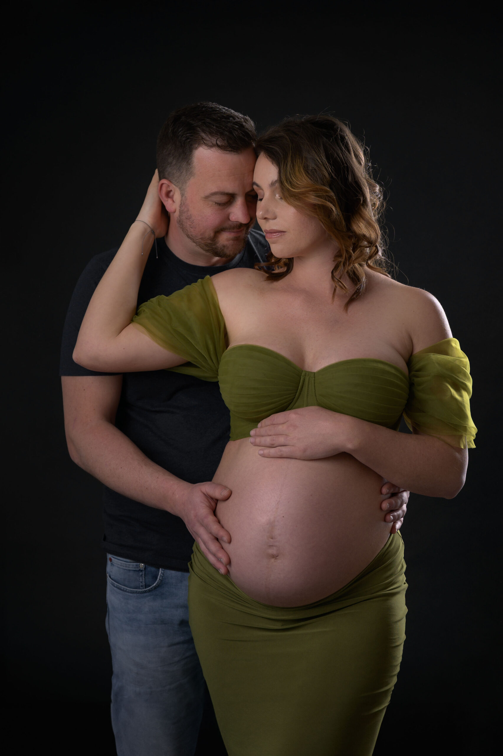 Schwangere im olivgrünen Tüllkleid mit Partner